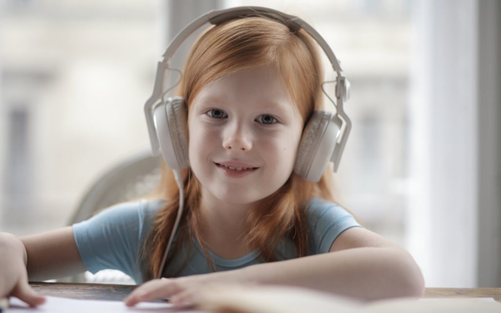 A young girl wearing headphones smiles