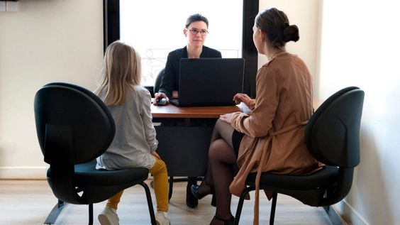 Teacher sitting with a student and her mother