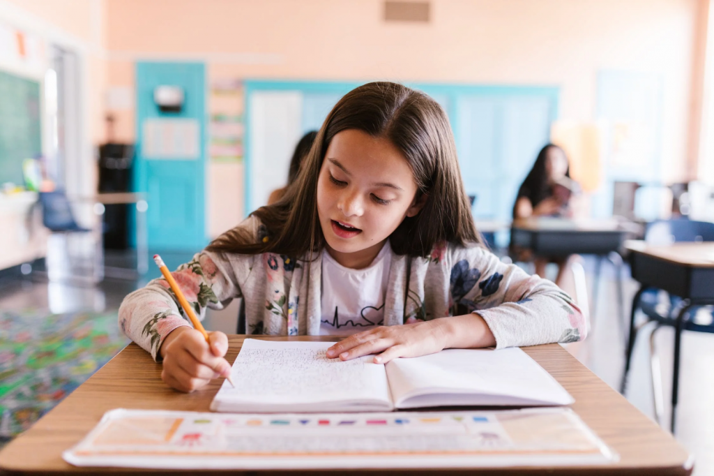 A girl writes on a notebook at her desk