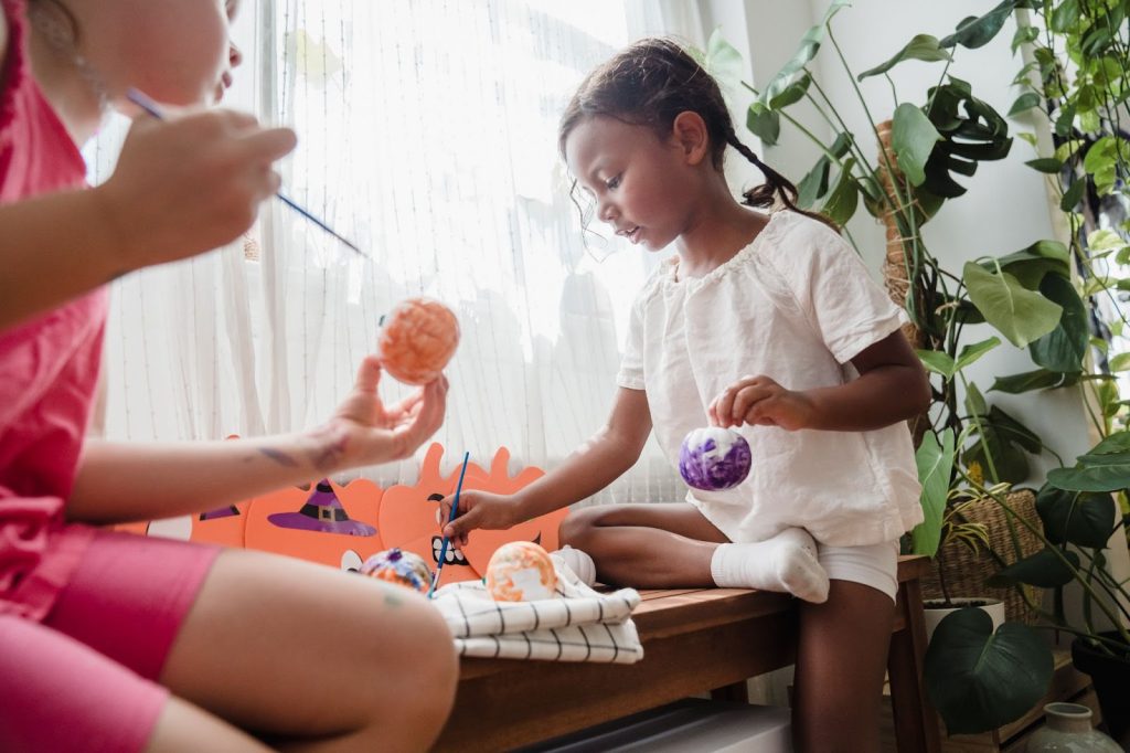 Little kids painting small pumpkins for Halloween decoration