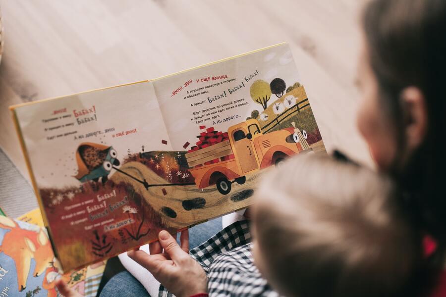 A woman and her toddler reading a book together