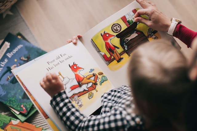 Child reading an interactive book with parent