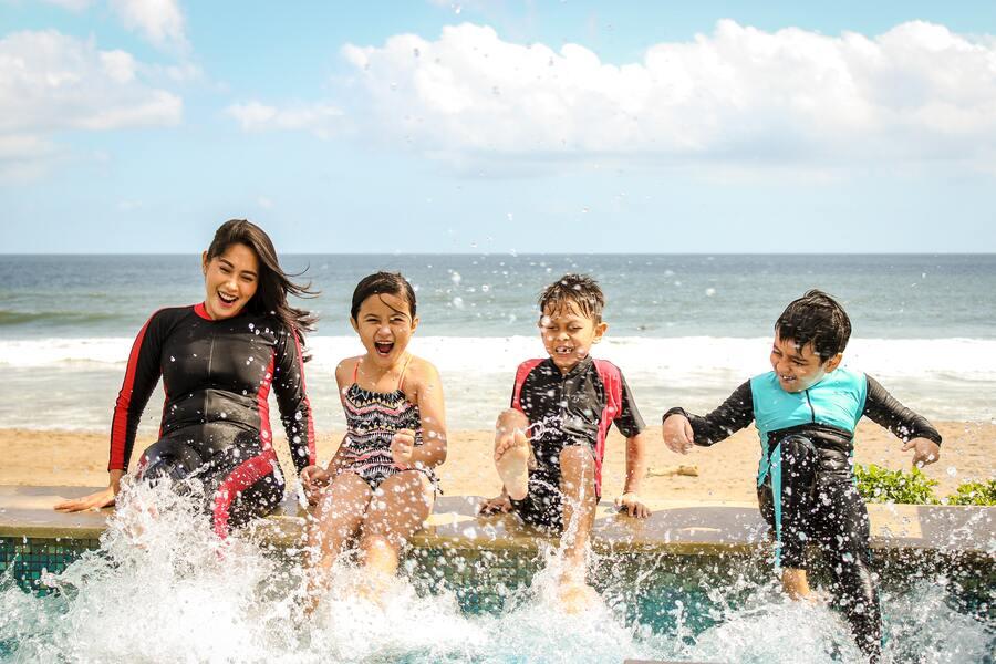 A woman and three children playing with water