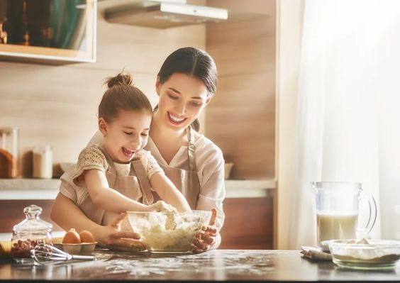 Little girl helping her mother bake cookies