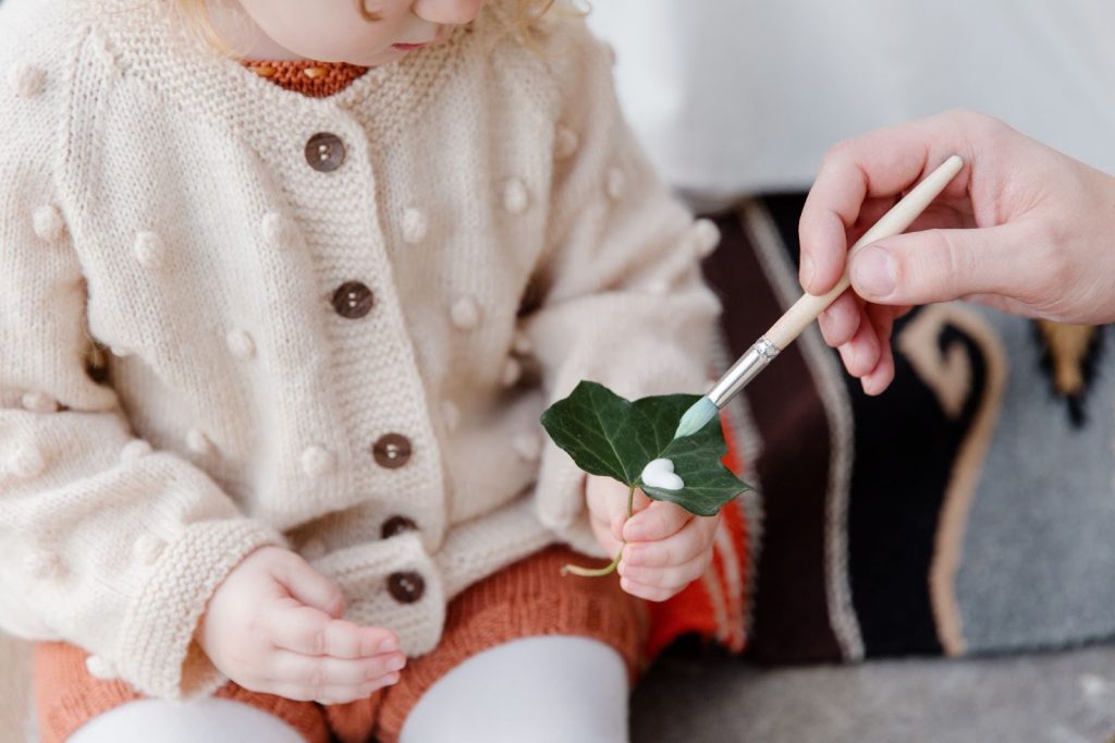 Father helping daughter with leaf painting