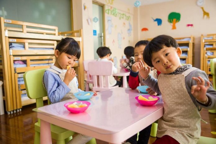 Toddlers sitting on a table and eating