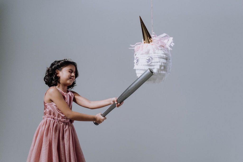 A girl holds a baseball bat in front of a piñata