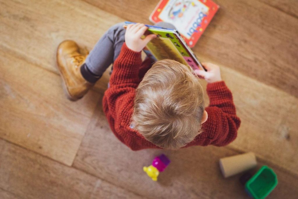 Kid with a book in hand on the floor