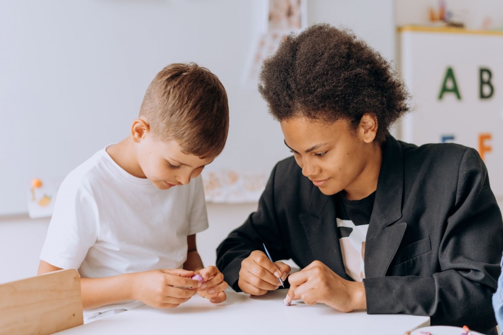 A Boy Sitting at the table with His Teacher