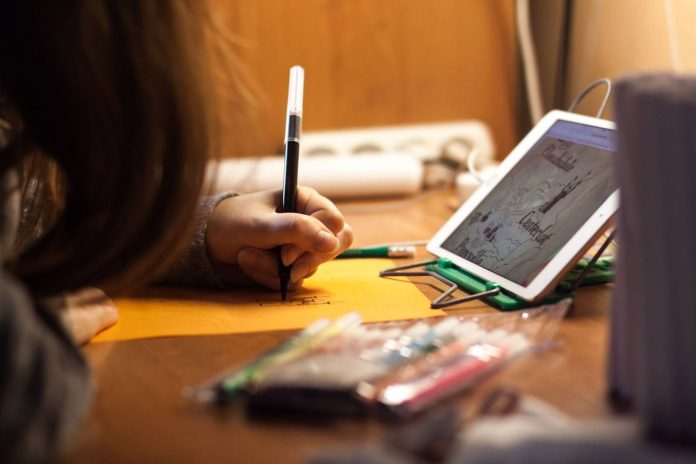 Small girl writing on orange paper