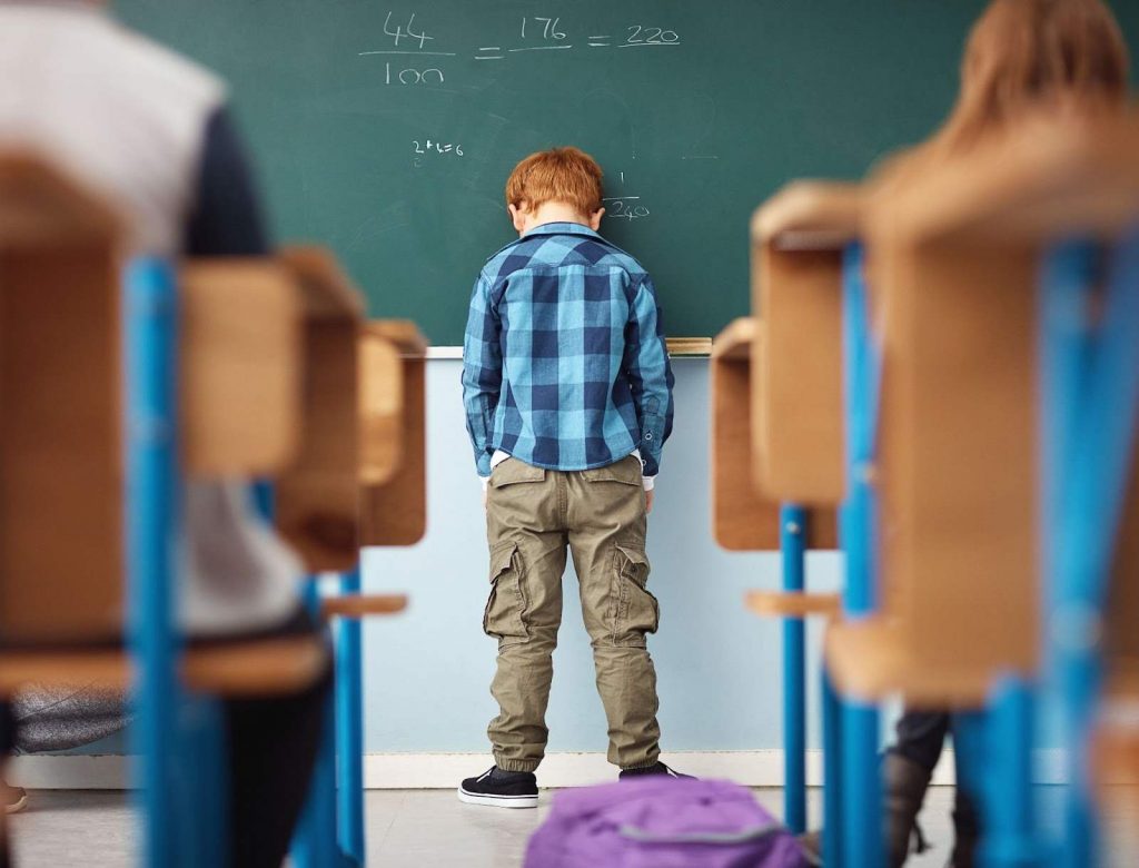 A boy feeling frustrated and overwhelmed with math, resting his head on the board