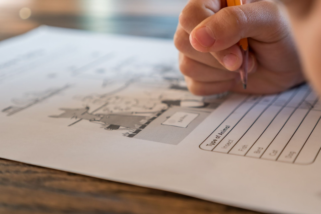 Kid holding pencil on printed paper