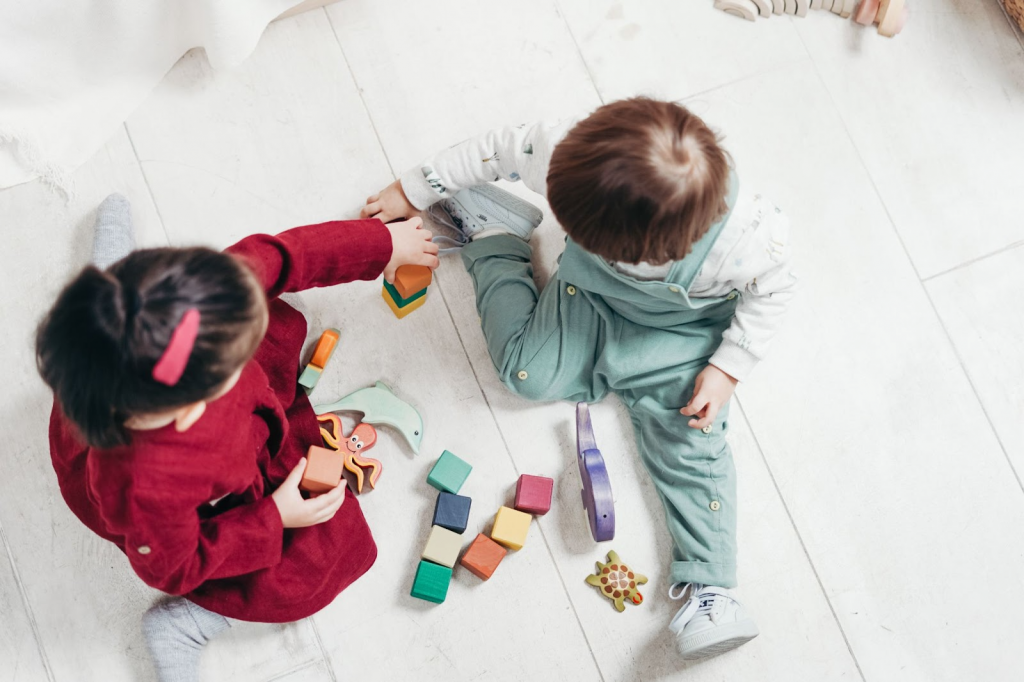 Two Children Sitting Down Playing With Lego Blocks