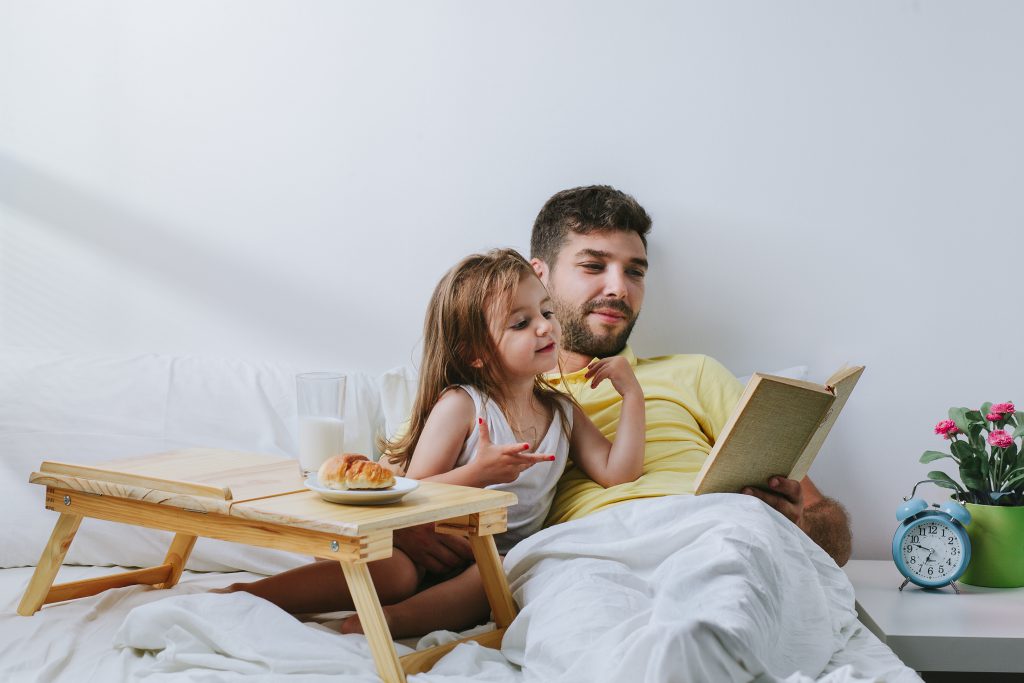 Father and daughter enjoying bed in breakfast