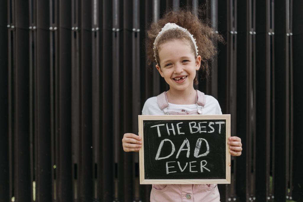 A girl holding a slate with the best dad ever written on it