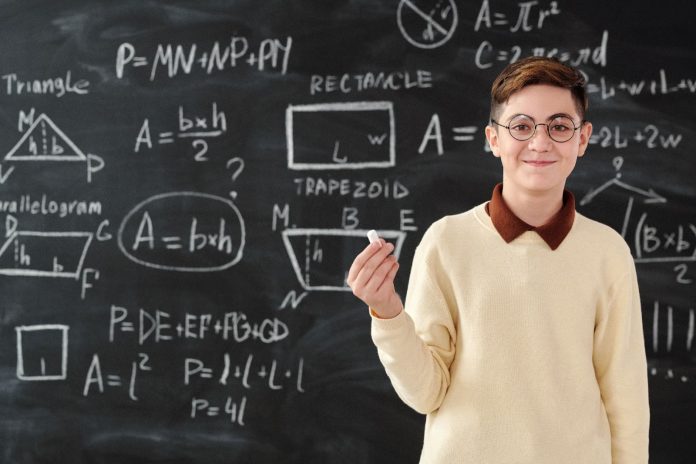 A Boy Holding a Chalk in a Math Class