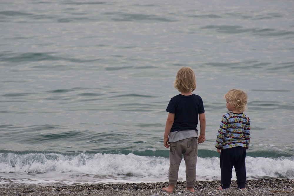 Children standing on beach watching the ocean