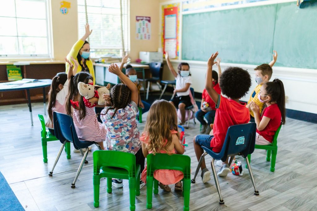 Teacher and kids sitting on chair in classroom