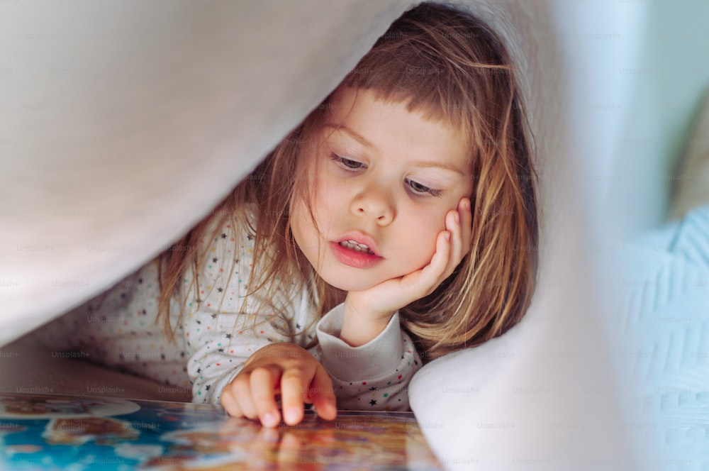 Little girl reading a book on bed