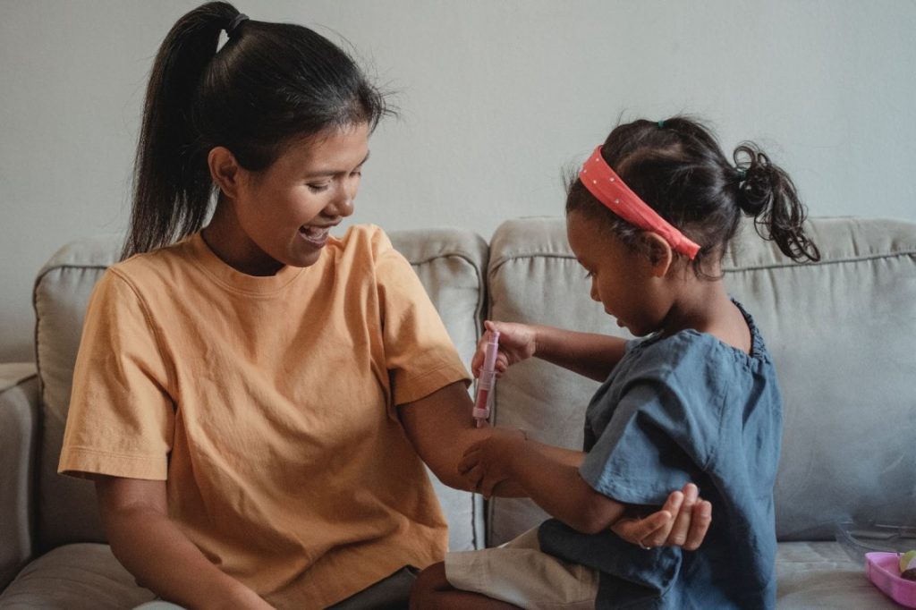 Mother and daughter playing with toy syringe