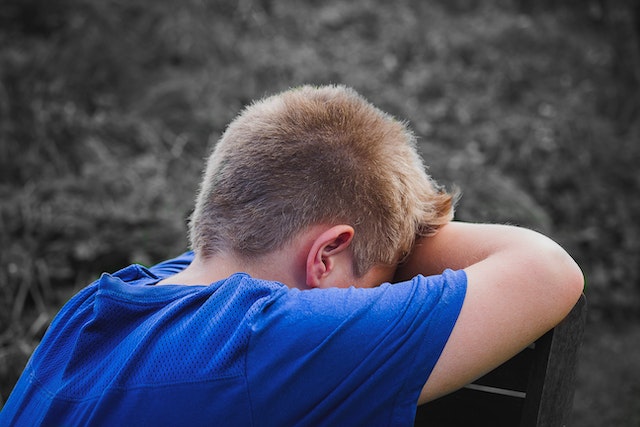 A boy resting his head on the chair