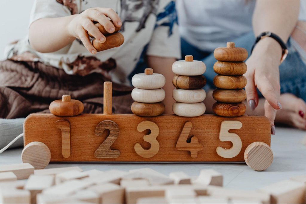 A child and mother playing with a wooden abacus