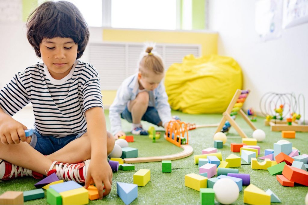 Two boys playing with wooden blocks in a room