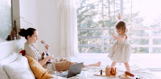 Happy woman playing ukulele for daughter