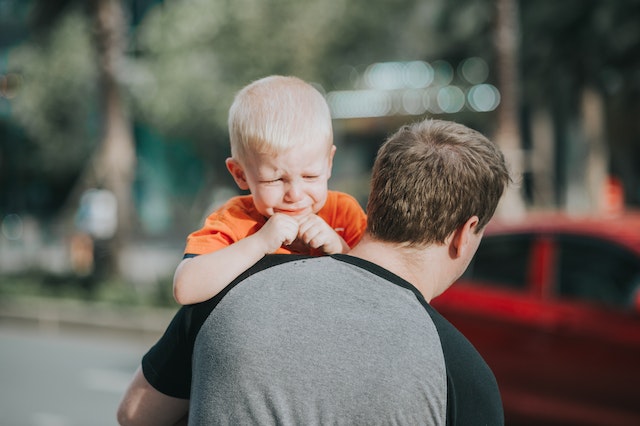 Child crying on father’s shoulders