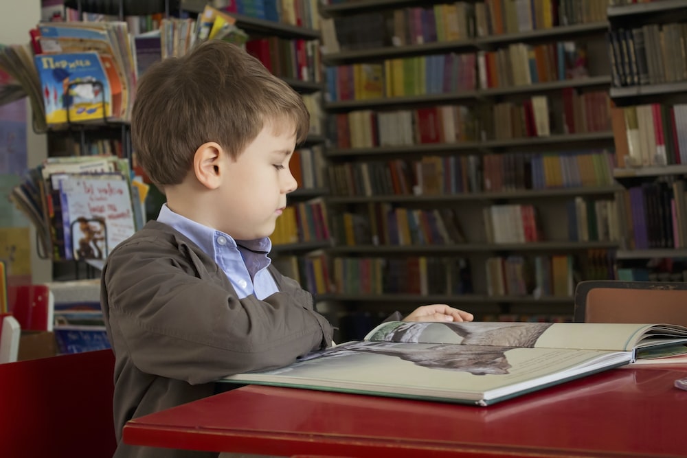 A boy reading a book in a library