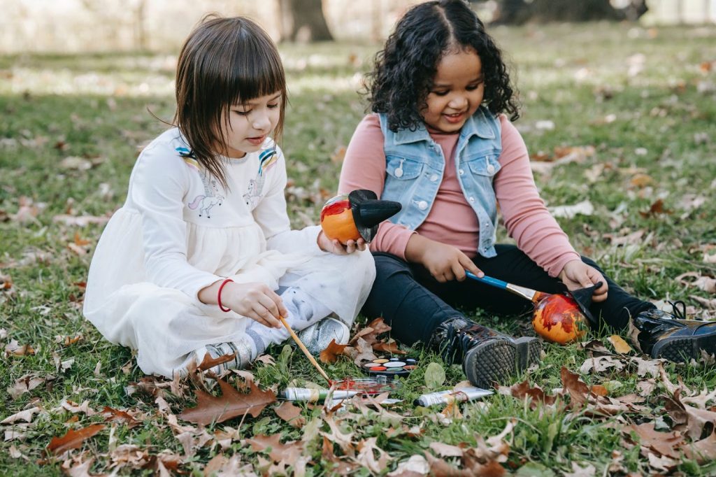 Two kids coloring pumpkin in park
