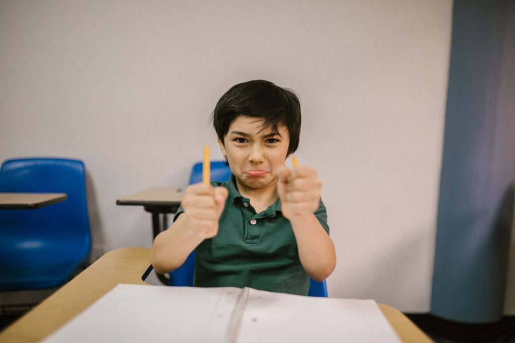 Boy Sitting on His Desk Looking Angry