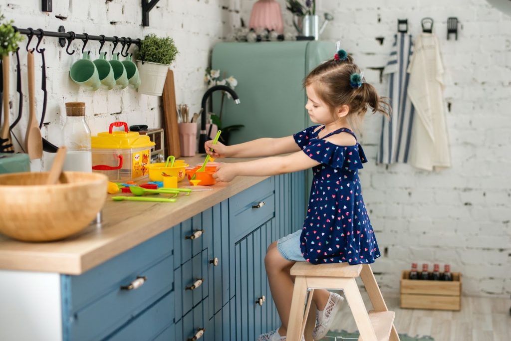 Girl Sitting on a Wooden Stool Playing on a Kitchen Counter