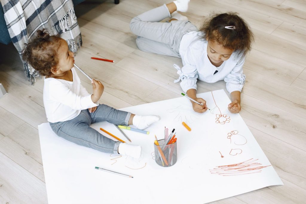 Two girls drawing on a chart paper