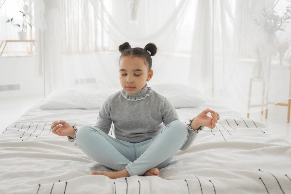 Little girl meditating on her bed