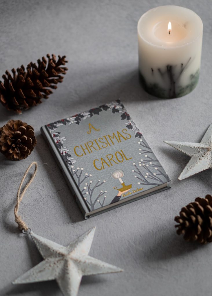 A book titled A Christmas Carol against a gray cushioned backdrop