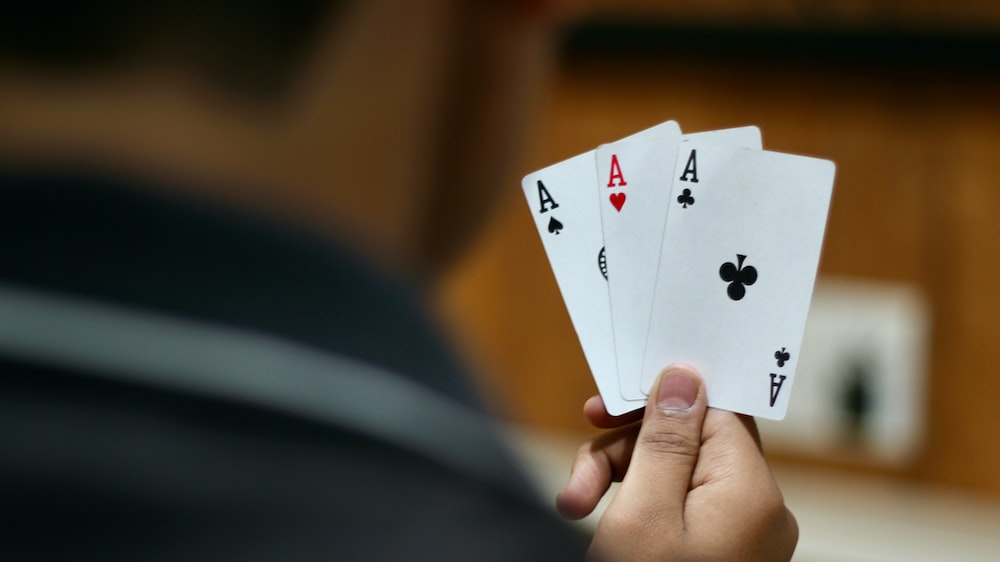 A kid holding 3 Aces of cards