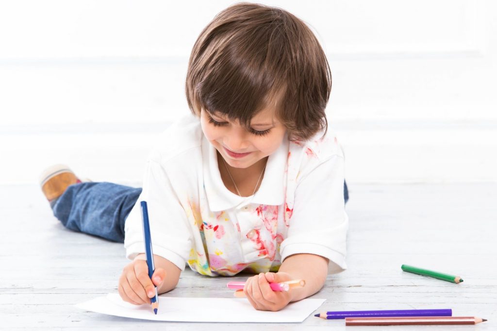 Kid drawing while lying on the floor