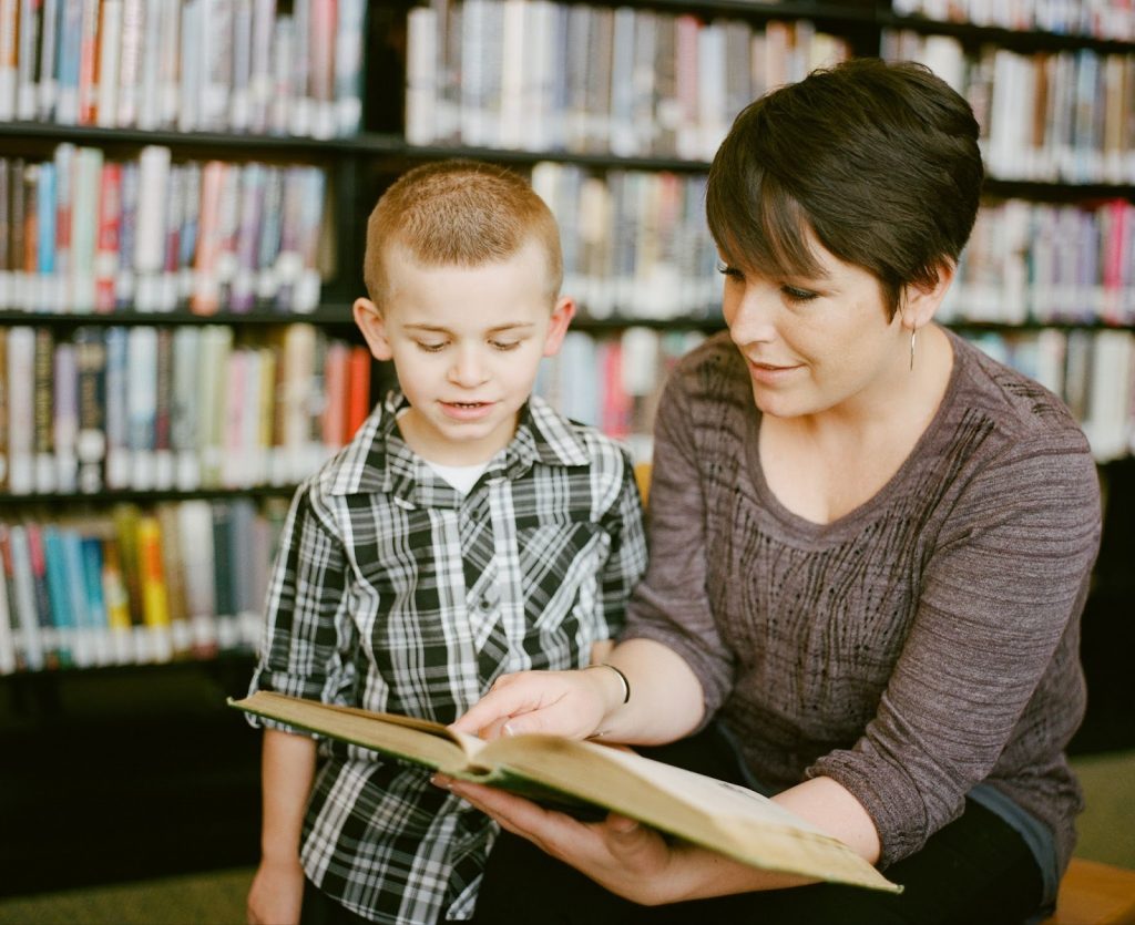 Little boy being taught to read by his teacher