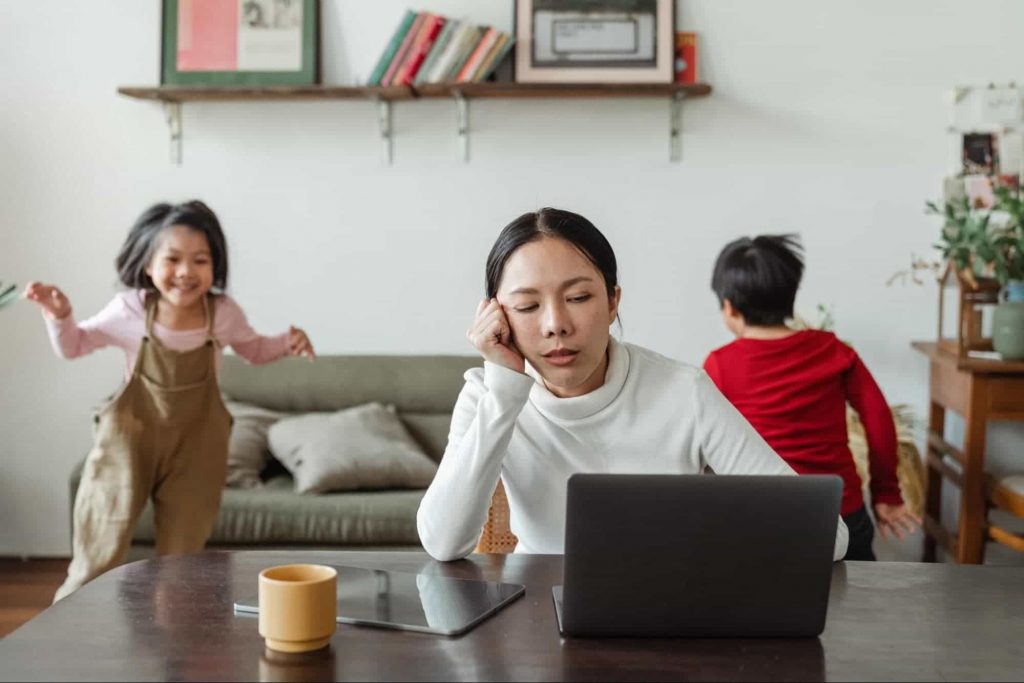 Working women on laptop and children are playing in background