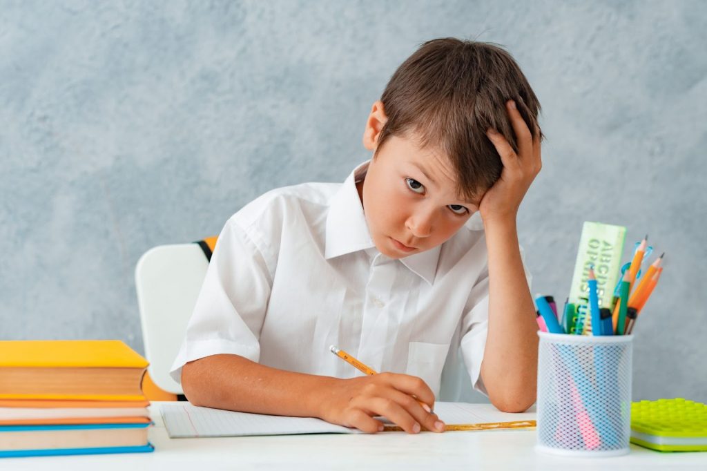 Kid resting his head while studying