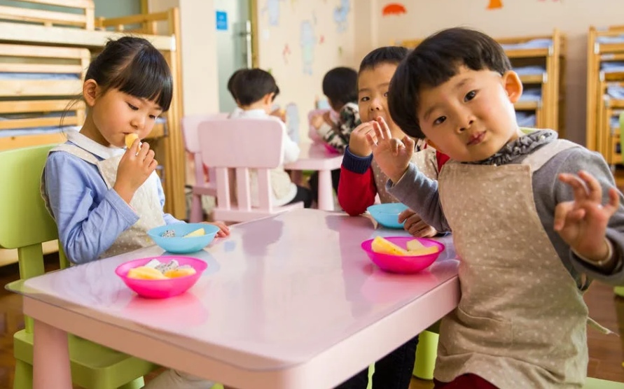 Toddlers eating food during school lunch