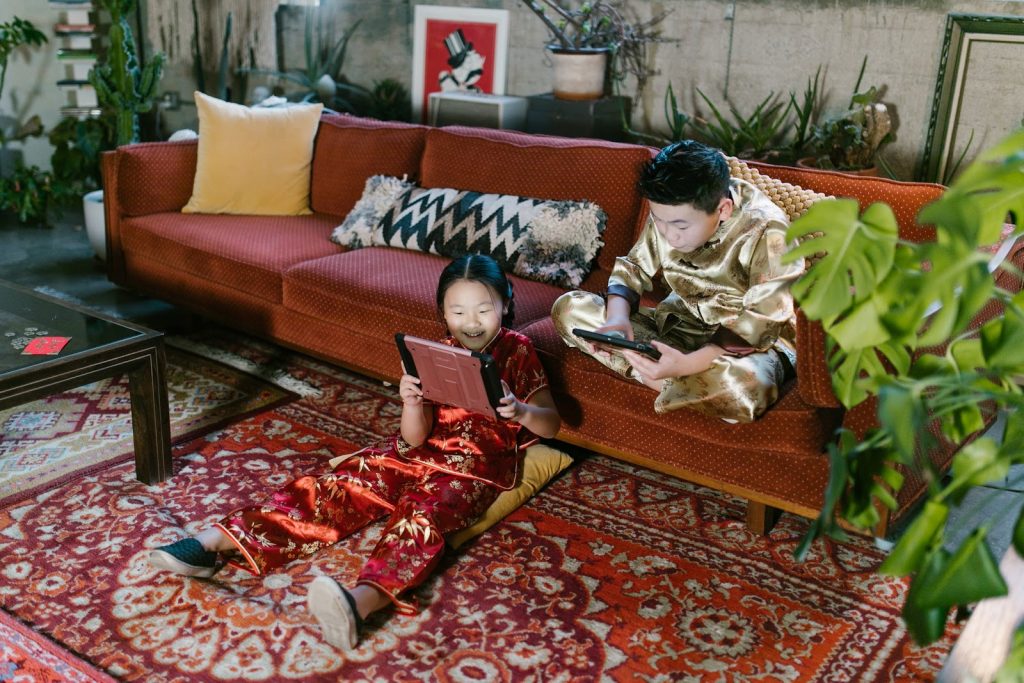 Young boy girl sitting in the living room playing games on tablets