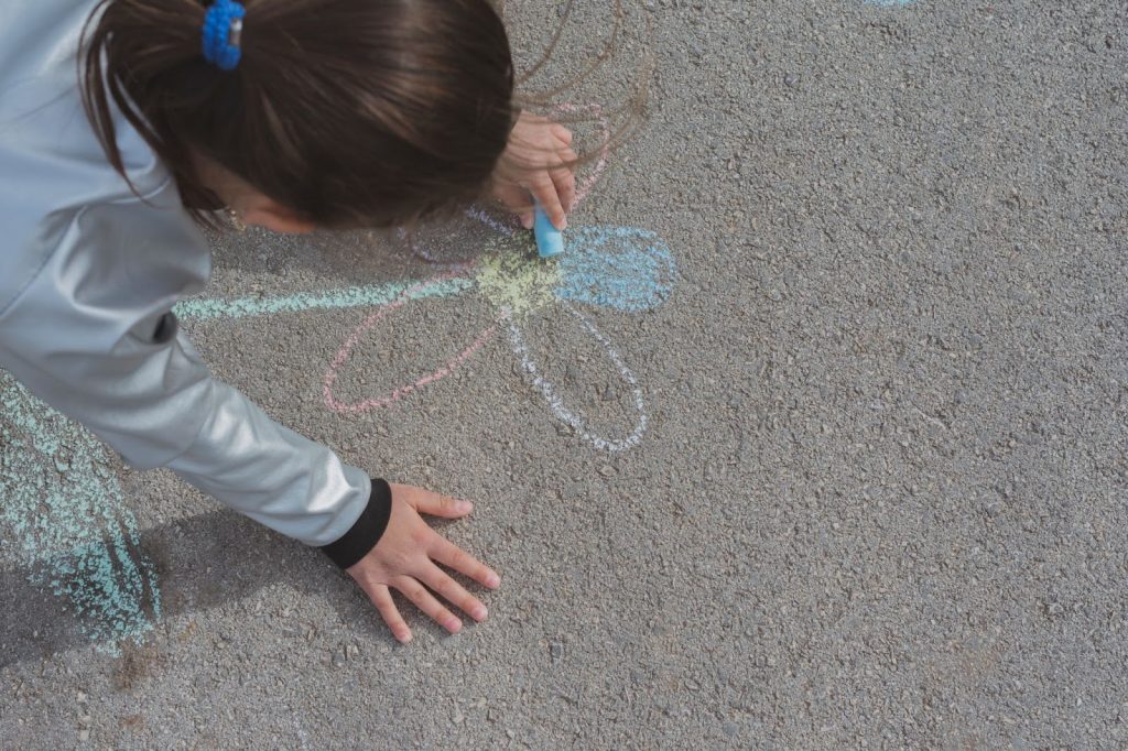 Girl drawing with chalk on pavement