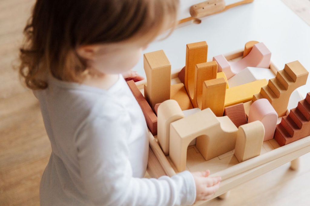 Little girl playing with wooden blocks on a table