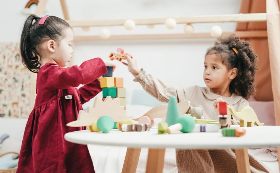 Two girls playing with wooden blocks