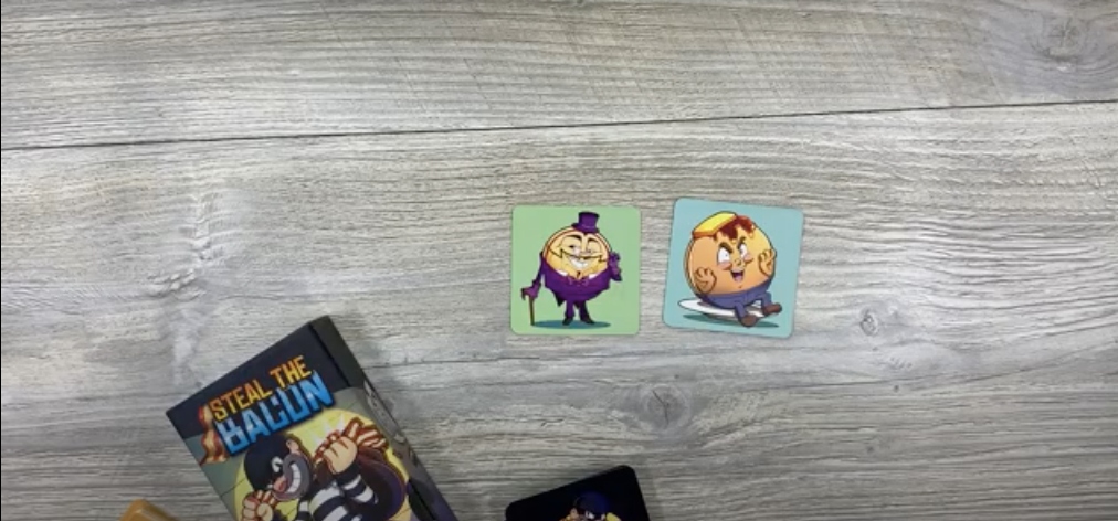 Steal the Bacon pack of cards and two open cards from the pack on a table