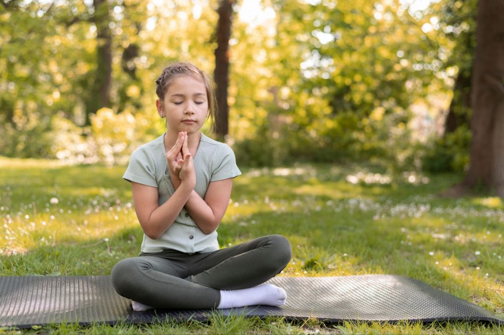 Little girl meditating on yoga mat
