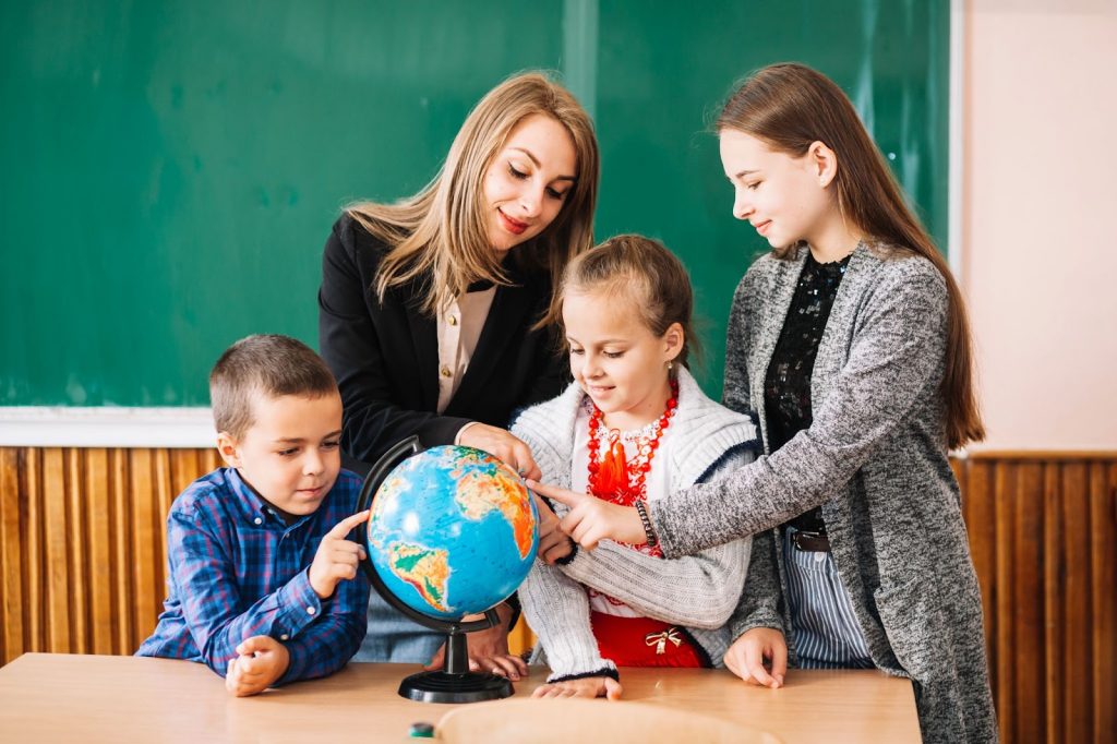 Teacher and students looking at a globe