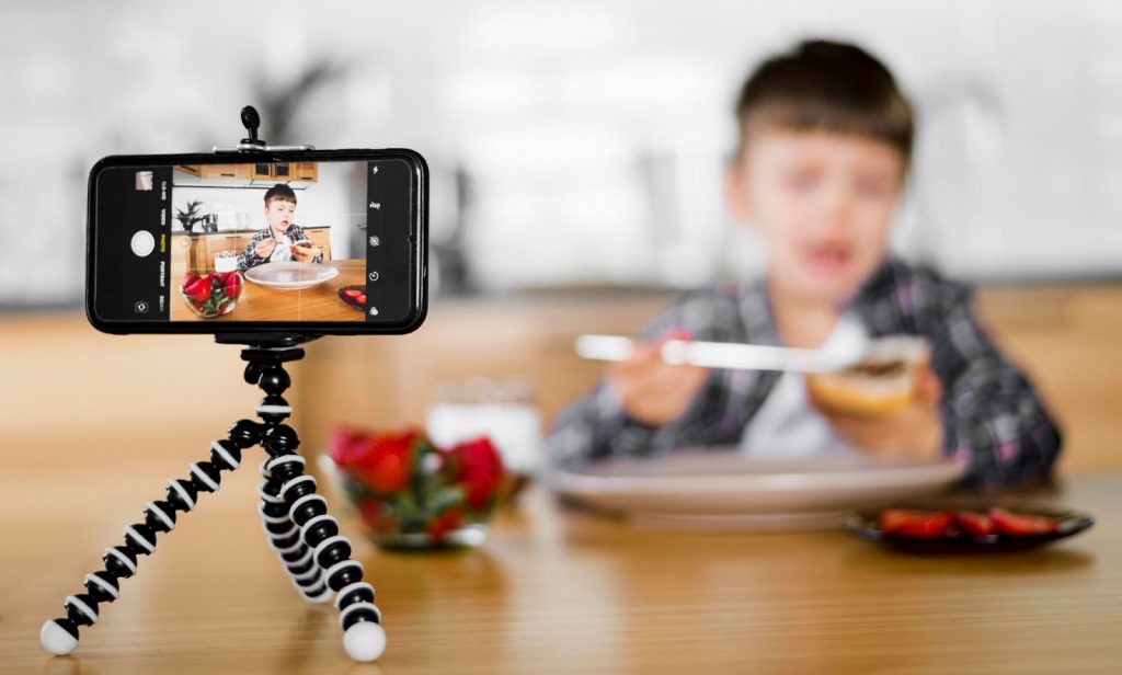 A phone attached to tripod recording a child eating